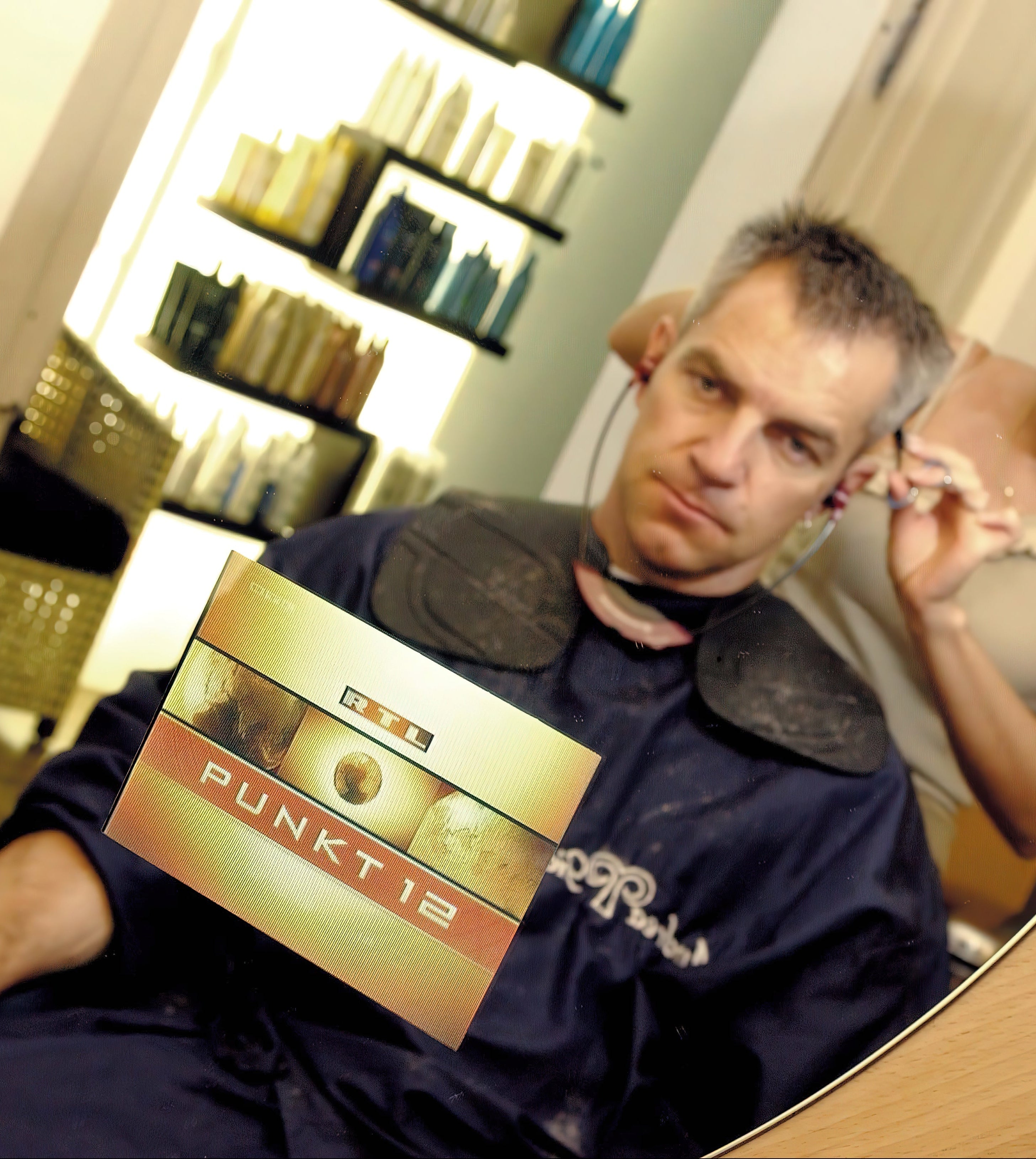 Man receiving a haircut in a salon with a 'Punkt 12' box.